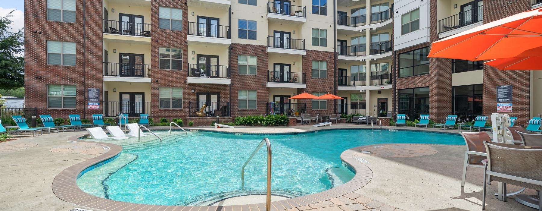 Resort-style pool with sun deck and lounge areas, set against the backdrop of Jones Grant luxury apartments in Raleigh, NC.
